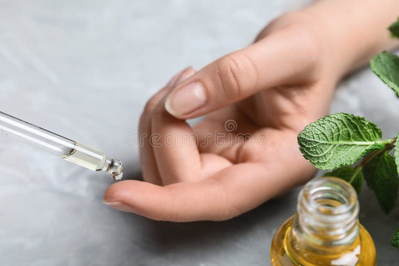 Woman dripping essential oil onto her finger at table