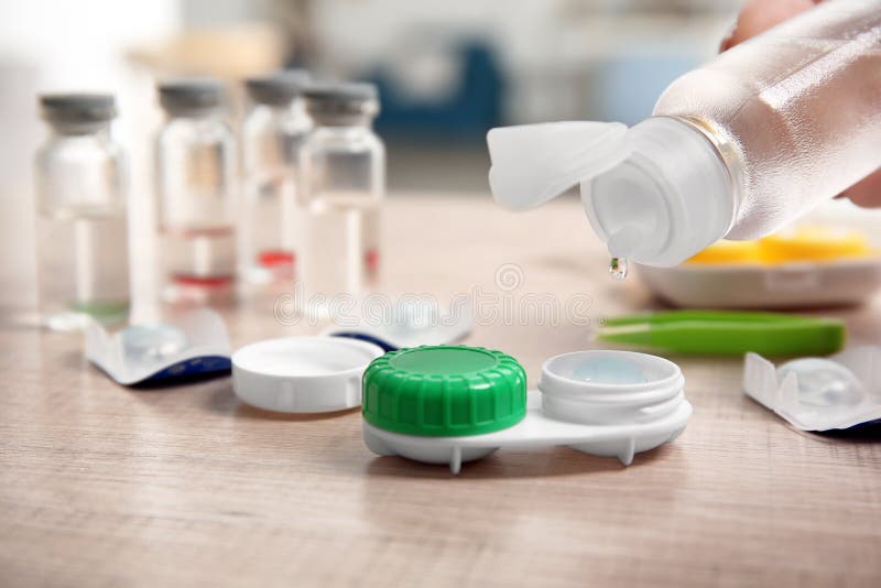 Woman dripping solution into contact lens case on table