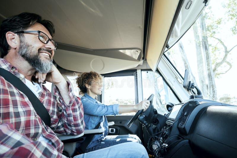 Woman Driver Driving a Camper Van with Happy Man on Passenger Seat. Alternative Couple Enjoying