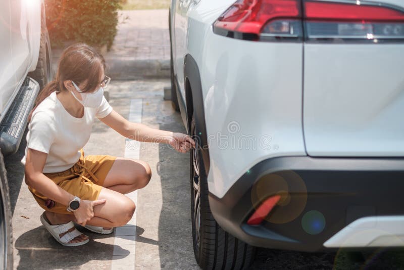 Woman driver hand inflating tires of vehicle, removing tire valve nitrogen cap for checking air pressure and filling air on car