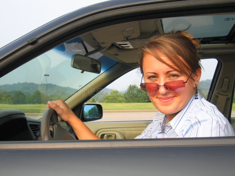 Donna che indossa occhiali da sole alla guida di un auto.