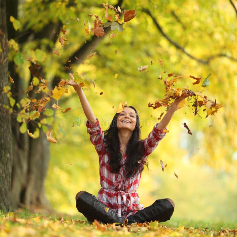 Woman drop leaves in autumn park