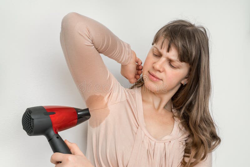 Woman is drying her sweating armpit with hair dryer stock images Woman is drying her sweating armpit with hair dryer stock images