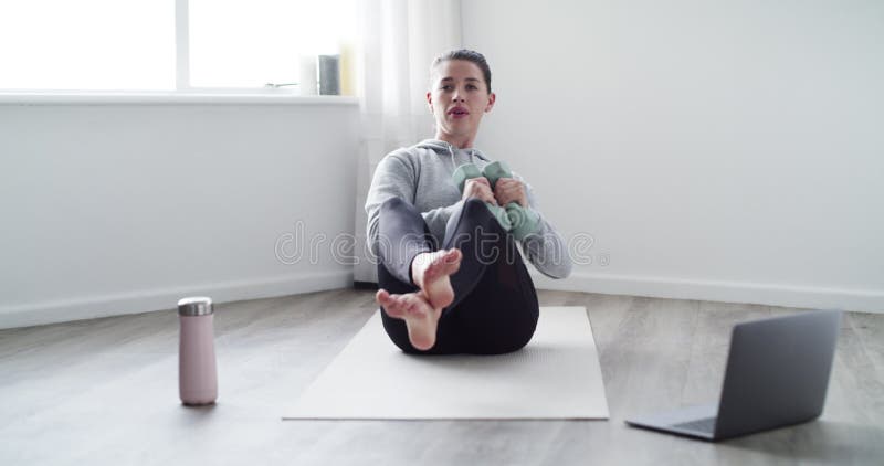 Woman, dumbbell and weight lifting for workout with laptop, breathing and yoga mat in living room of home. Person, face