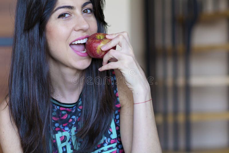 Woman eating apple smiling happy looking at camera. stock photo Woman eating apple smiling happy looking at camera. stock photo