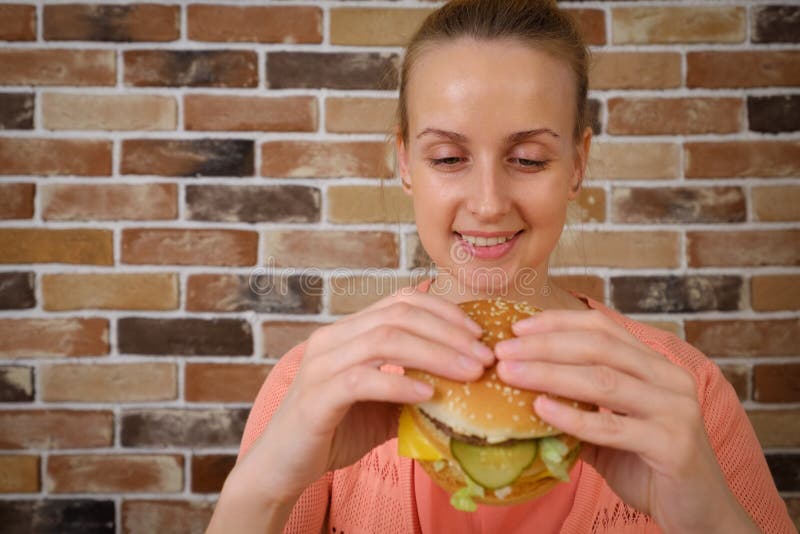 Woman eating big burger and smiling royalty free stock photos