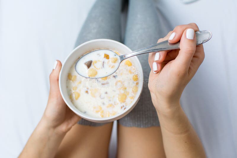 Woman eating cereals in bed top view