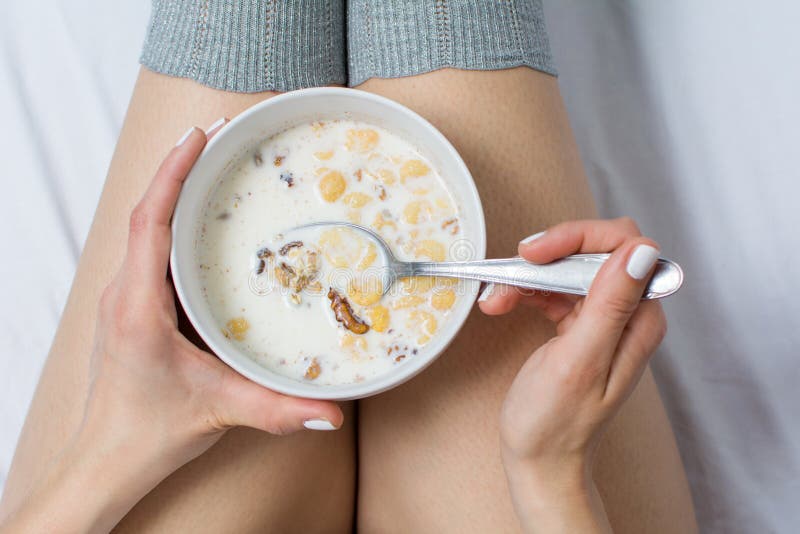 Woman eating cereals in bed top view
