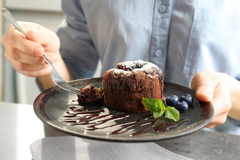Woman eating delicious fresh fondant with hot chocolate. At table. Lava cake recipe stock photography