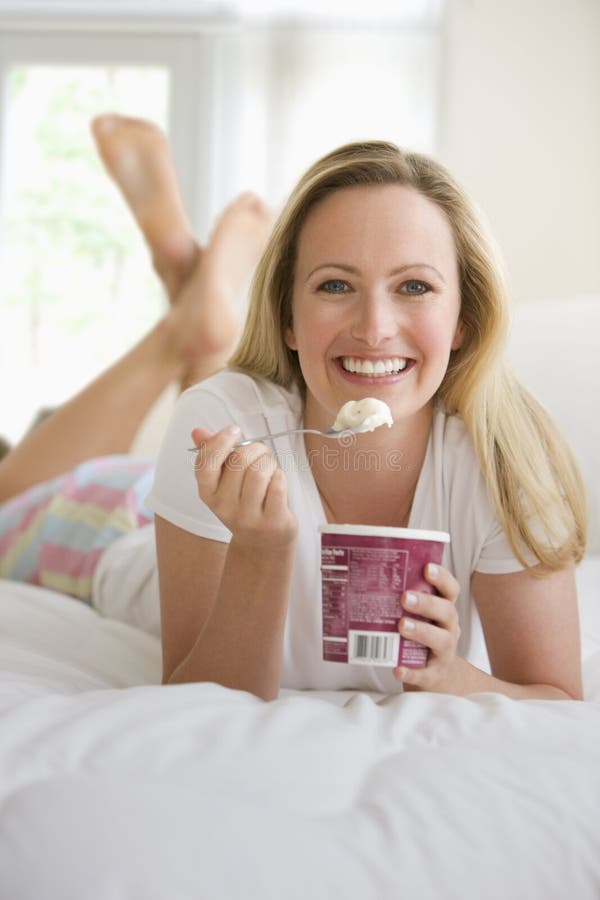 Woman Eating Ice Cream in Bed stock photos