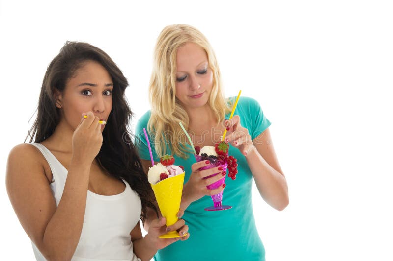 Black and white women eating ice cream with fresh fruit isolated over white background. Black and white women eating ice cream with fresh fruit isolated over white background