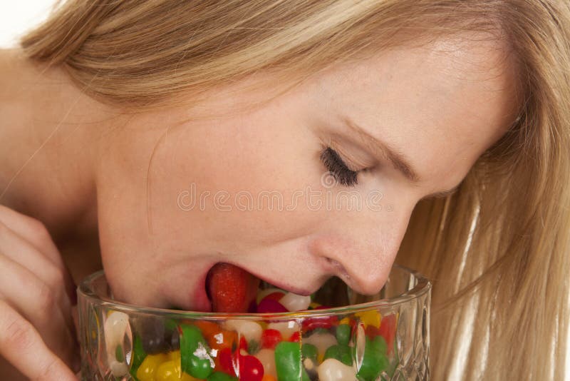Woman eating jellybeans tongue in bowl eyes closed