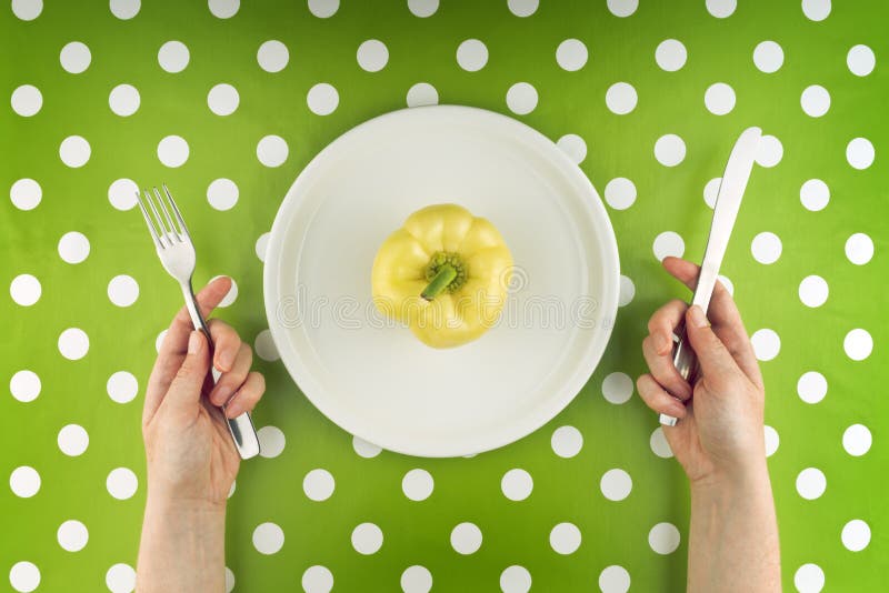 Woman eating raw yellow pepper, top view