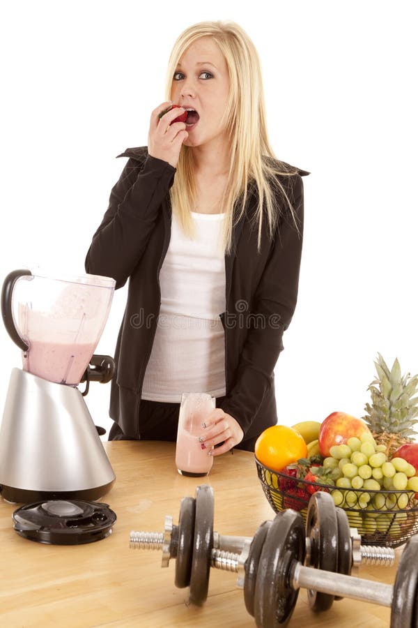 Woman eating strawberry by blender