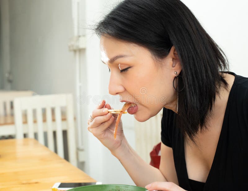 Transgender LGBT Asian Woman eats spicy hot tomyum noodle soup and hanging on chopstick to mouth with sweat delicious enjoy eating