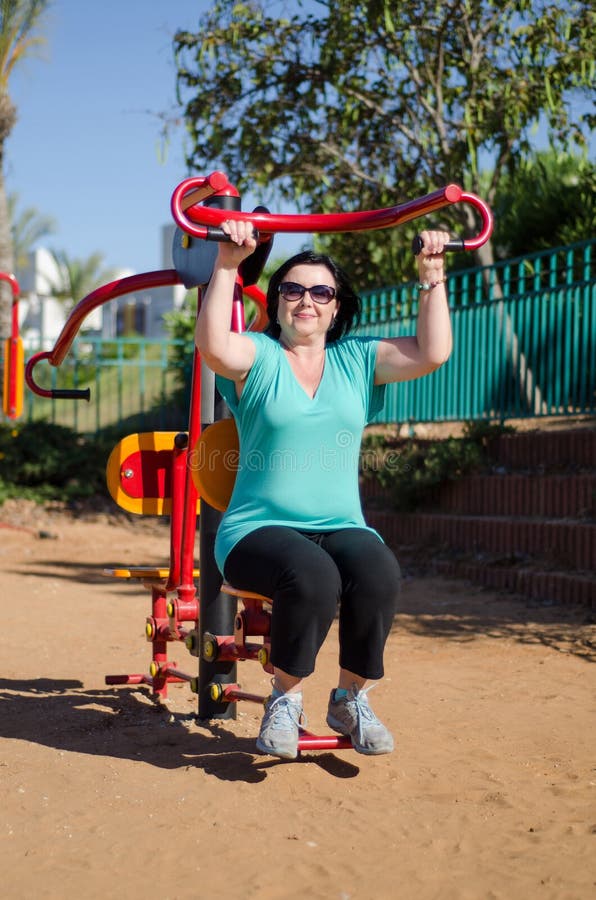 Woman enhancing her arms in fitness station