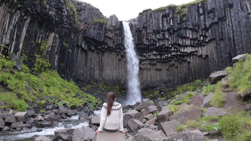 Woman enjoying majestic Svartifoss waterfall in Skaftafell on Iceland