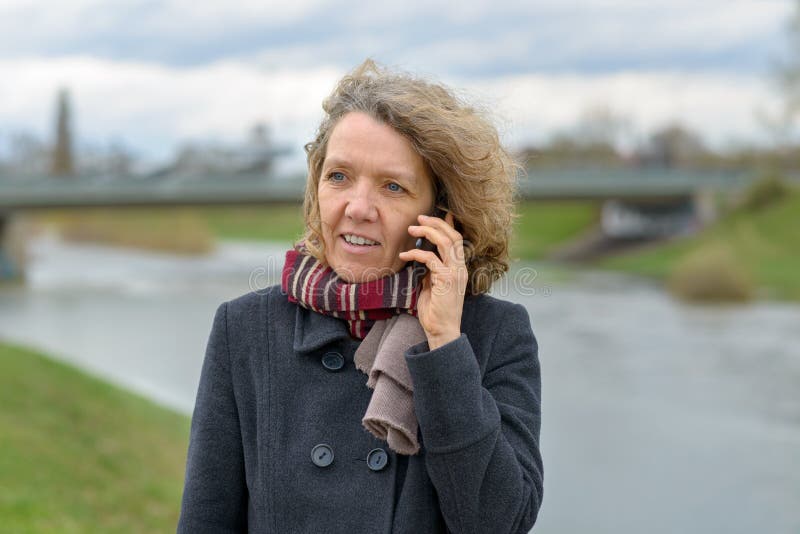 Woman enjoying a walk in winter using a mobile stock photo Woman enjoying a walk in winter using a mobile stock photo
