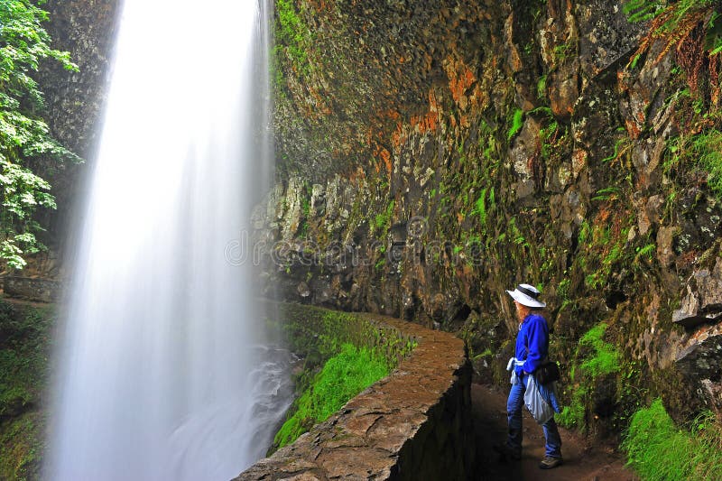 A female Hiker enjoying the rewards of her hike with the breath taking view from behind the cascading waterfall. A female Hiker enjoying the rewards of her hike with the breath taking view from behind the cascading waterfall.