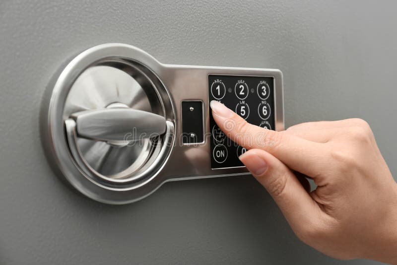 Woman entering code on keypad of safe, closeup