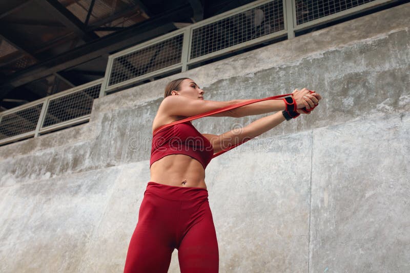 Woman Exercises With Resistance Band. Fitness Girl On Outdoor Workout In City. Sexy Female In Fashion Sporty Outfit.