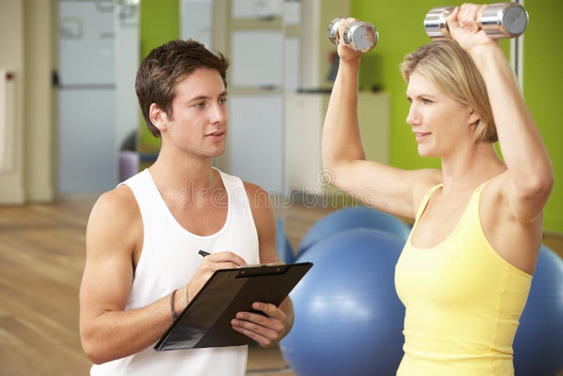Woman Exercising Being Encouraged By Personal Trainer In Gym stock photos Woman Exercising Being Encouraged By Personal Trainer In Gym stock photos
