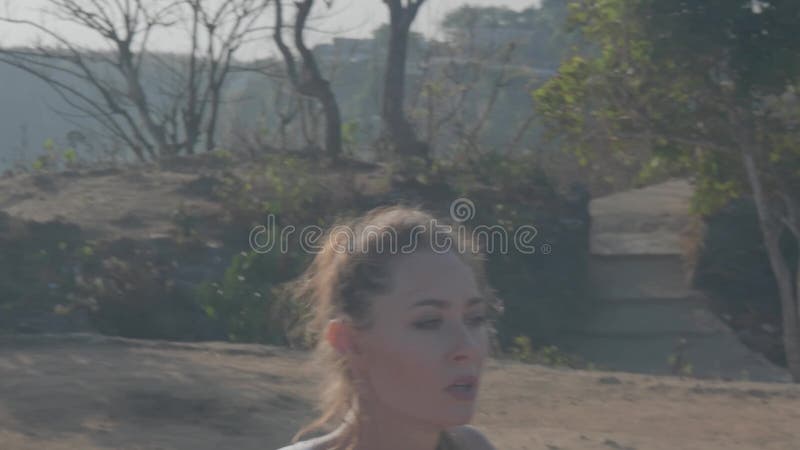 Woman exercising on sea shore cliff at sunrise