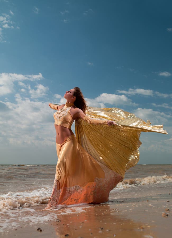 Woman in exotic dress standing on the beach