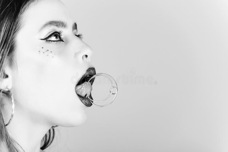 Woman with fashionable makeup hold jewelry earring on tongue stock photography Woman with fashionable makeup hold jewelry earring on tongue stock photography