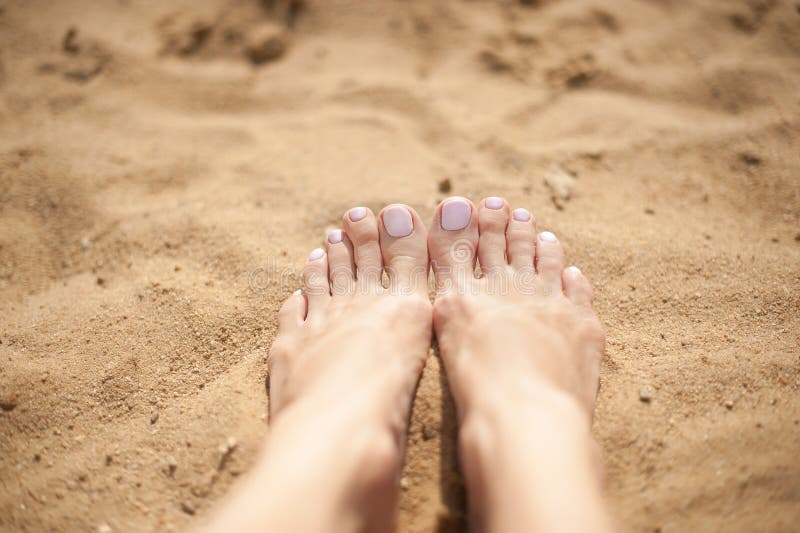 Woman feet with light pink toenails on the sand royalty free stock photo Woman feet with light pink toenails on the sand royalty free stock photo