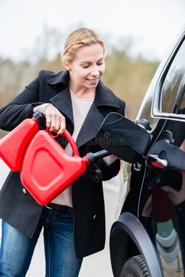 Woman filling car up with gas from the spare canister stock photography Woman filling car up with gas from the spare canister stock photography