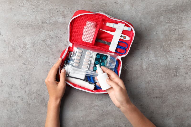 Woman with first aid kit on gray background