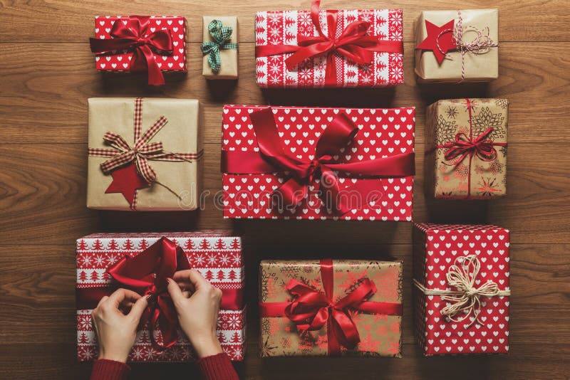 Woman fixing a bow on beautifuly wrapped vintage christmas presents on wooden background royalty free stock images