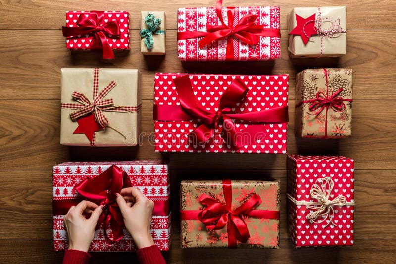 Woman fixing a bow on beautifuly wrapped vintage christmas presents on wooden background stock photo