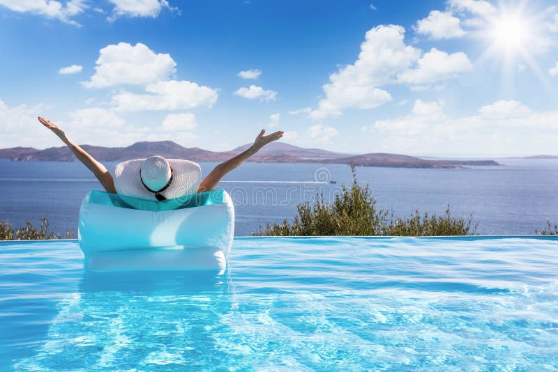 Woman floats on a pool with view to the Mediterranean sea stock photo Woman floats on a pool with view to the Mediterranean sea stock photo
