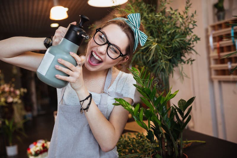 Woman florist with water sprayer watering flowers and shouting