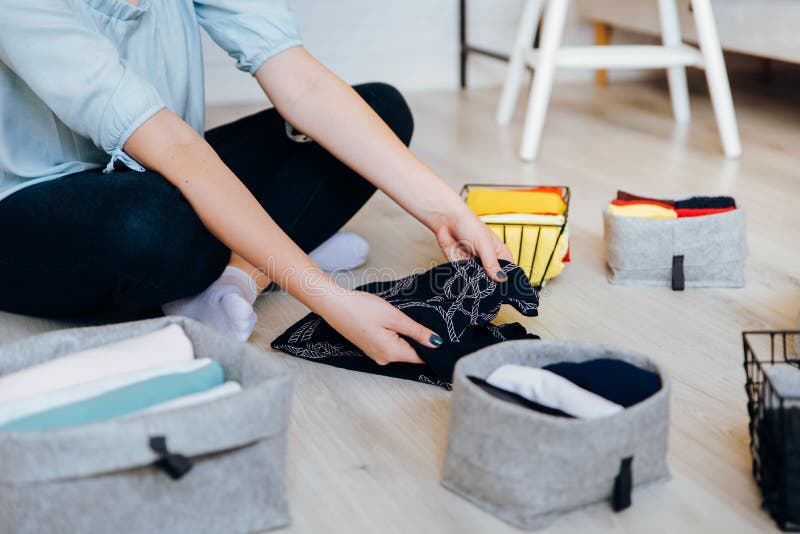 Woman folding clothes on the floor, organizing stuff and laundry