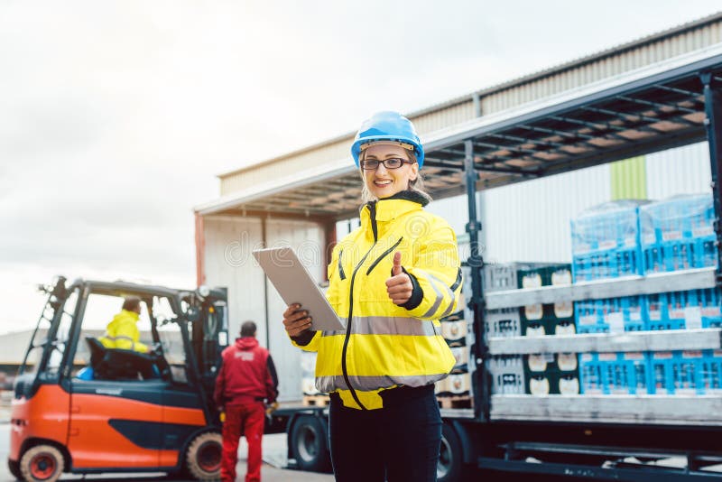 Woman in front of forklift transporting goods from warehouse stock image