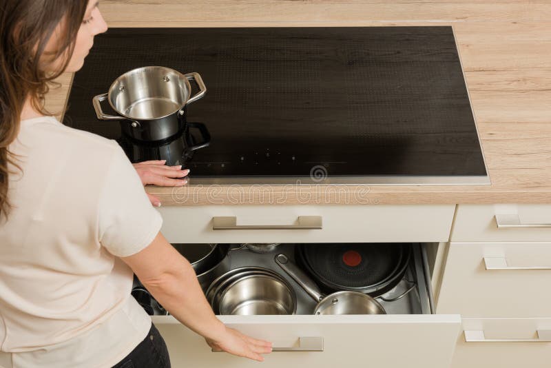 Woman in Front of Modern Cooker with Open Drawer Under the Stove Stock
