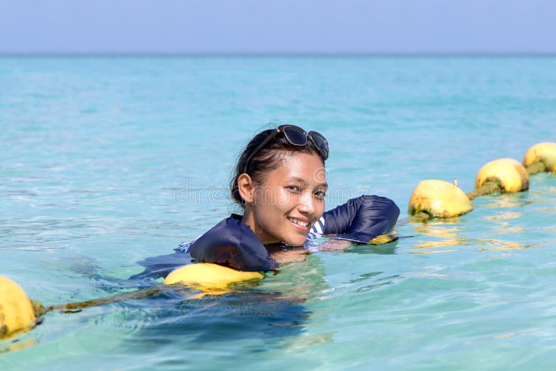 Woman in a Full-body Swimsuit Lying on Yellow Buoys Stock Photo - Image