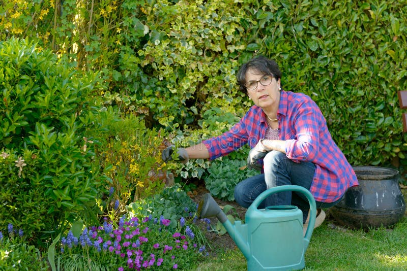 Happy Woman Planting Flowers At Her Backyard Stock Photo