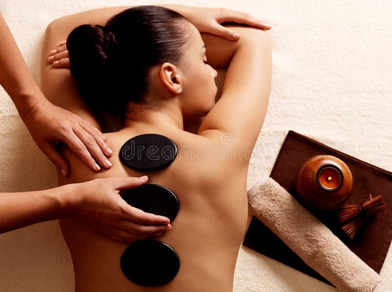 Young woman getting hot stone massage in spa salon. Beauty treatment concept.