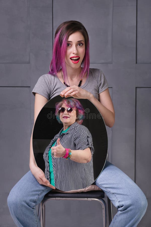 Concept of women getting old and looking stylish at the mirror. Girl is surprised by foresight of her appearance at senior age. Family of hipsters with pink hair. Concept of women getting old and looking stylish at the mirror. Girl is surprised by foresight of her appearance at senior age. Family of hipsters with pink hair