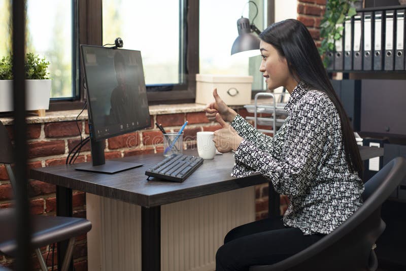 Woman gives thumbs up to remote coworker stock images