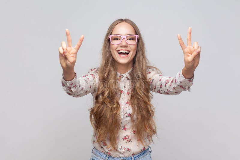 Woman in glasses showing v sign with fingers, peace or victory gesture, rejoicing success.