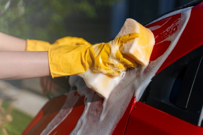 Woman in gloves washes the car with sponge