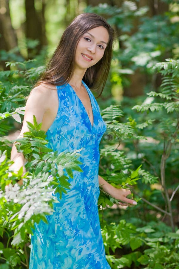 Woman among green leaves in the forest