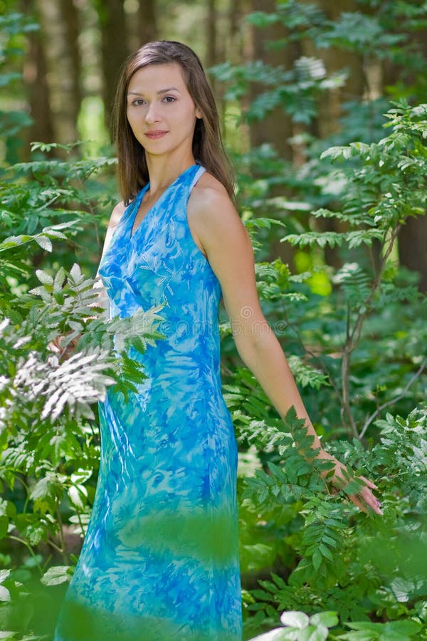 Woman among green leaves in the forest