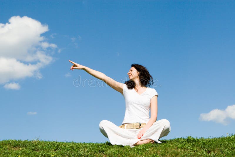 Woman on a green meadow and show something