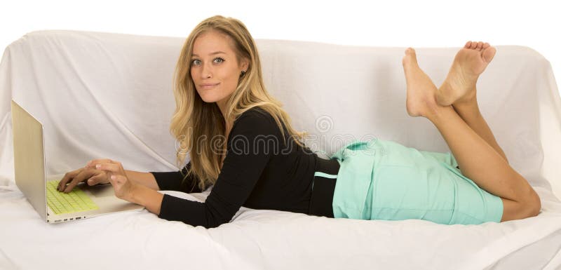A woman working on her laptop, relaxing on her couch with her feet up.